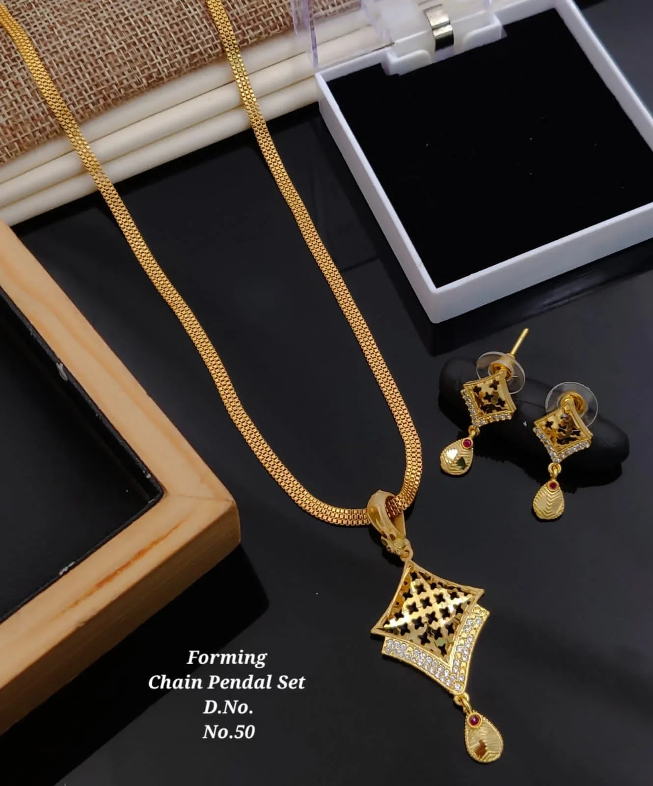 Gold forming chain pendant set with diamond accents and red gemstone drops displayed with earrings