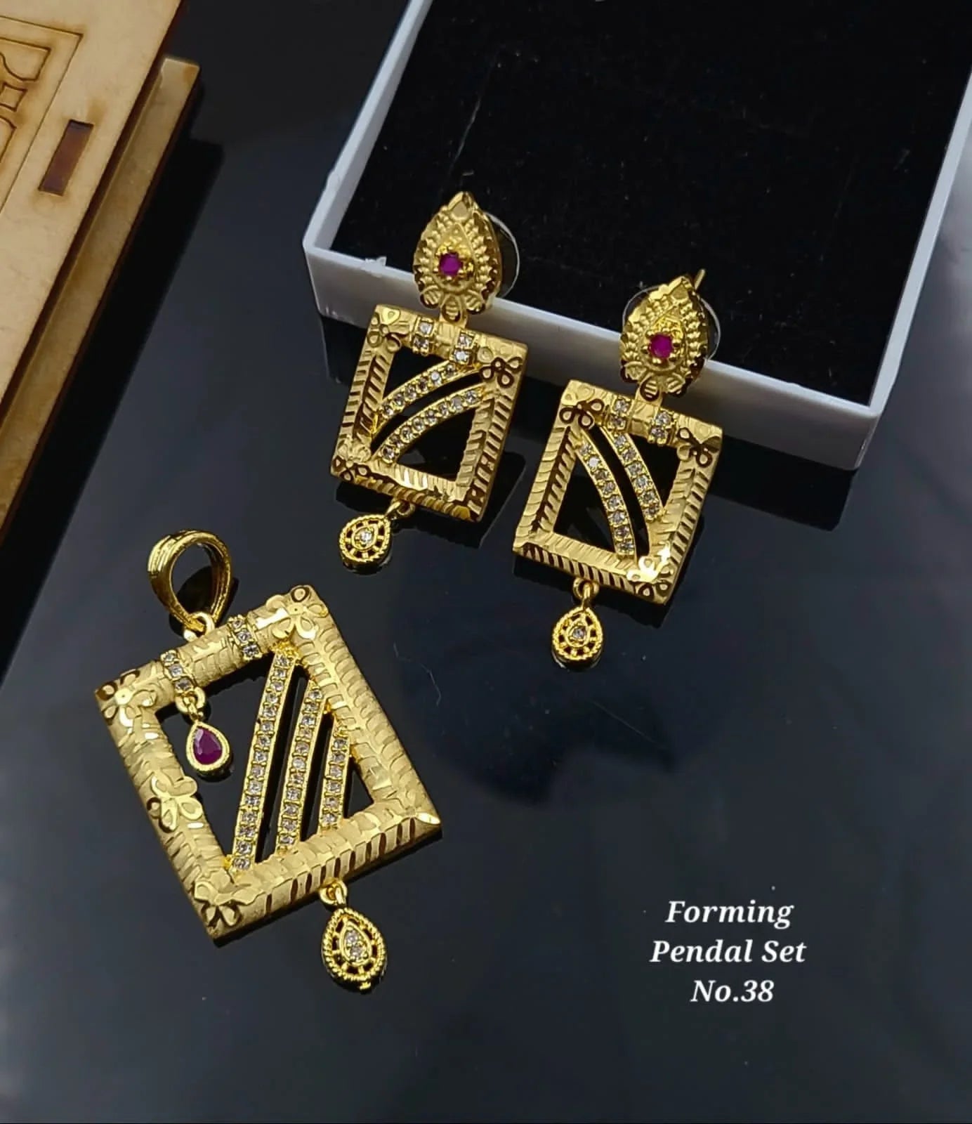 Gold forming pendant set No.38 with red stones and intricate design on black background