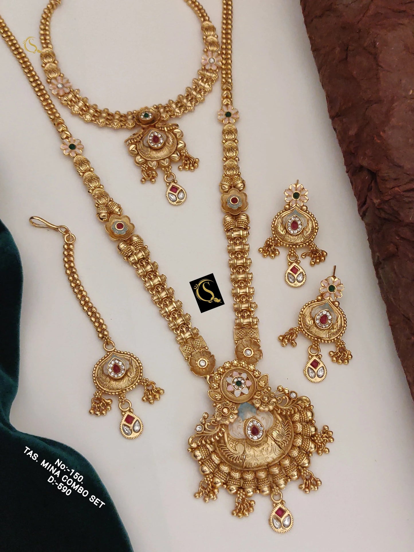 Traditional gold necklace set with intricate designs, red and green stones, including earrings and bracelet