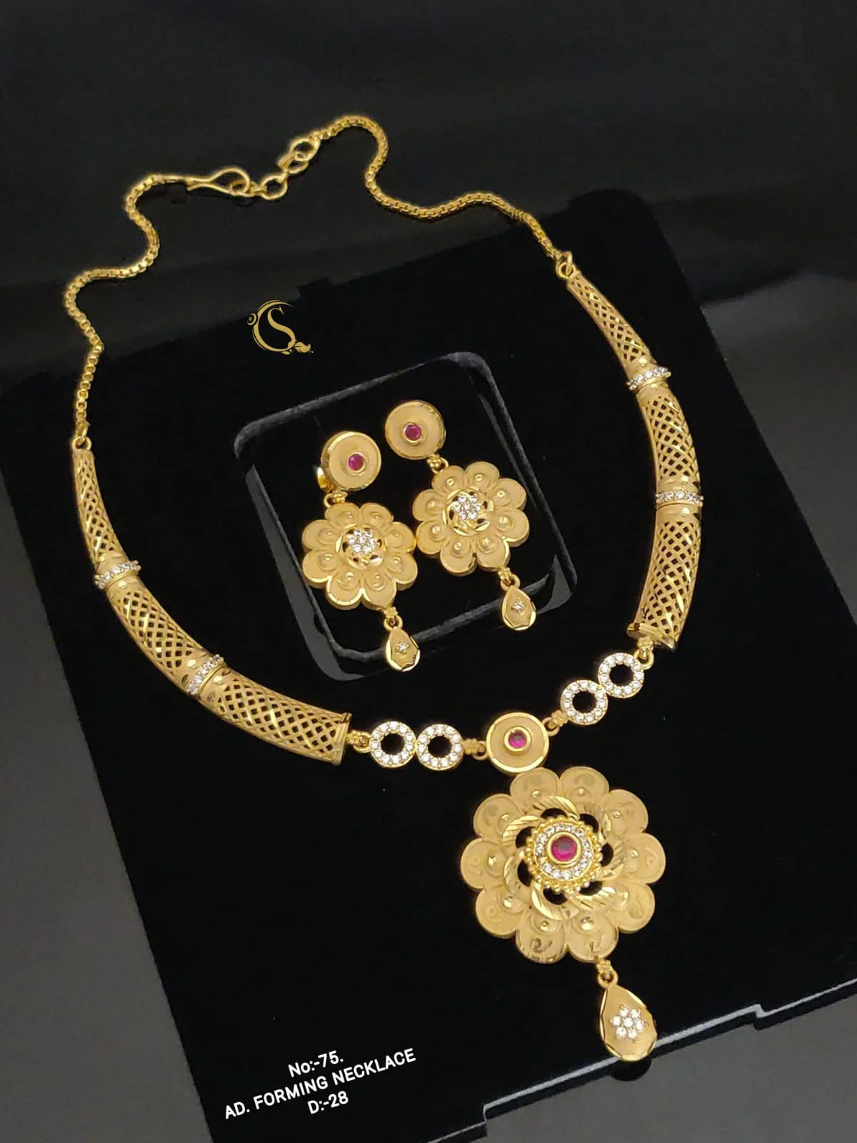 Gold necklace and matching floral earrings with red and white stones on black background